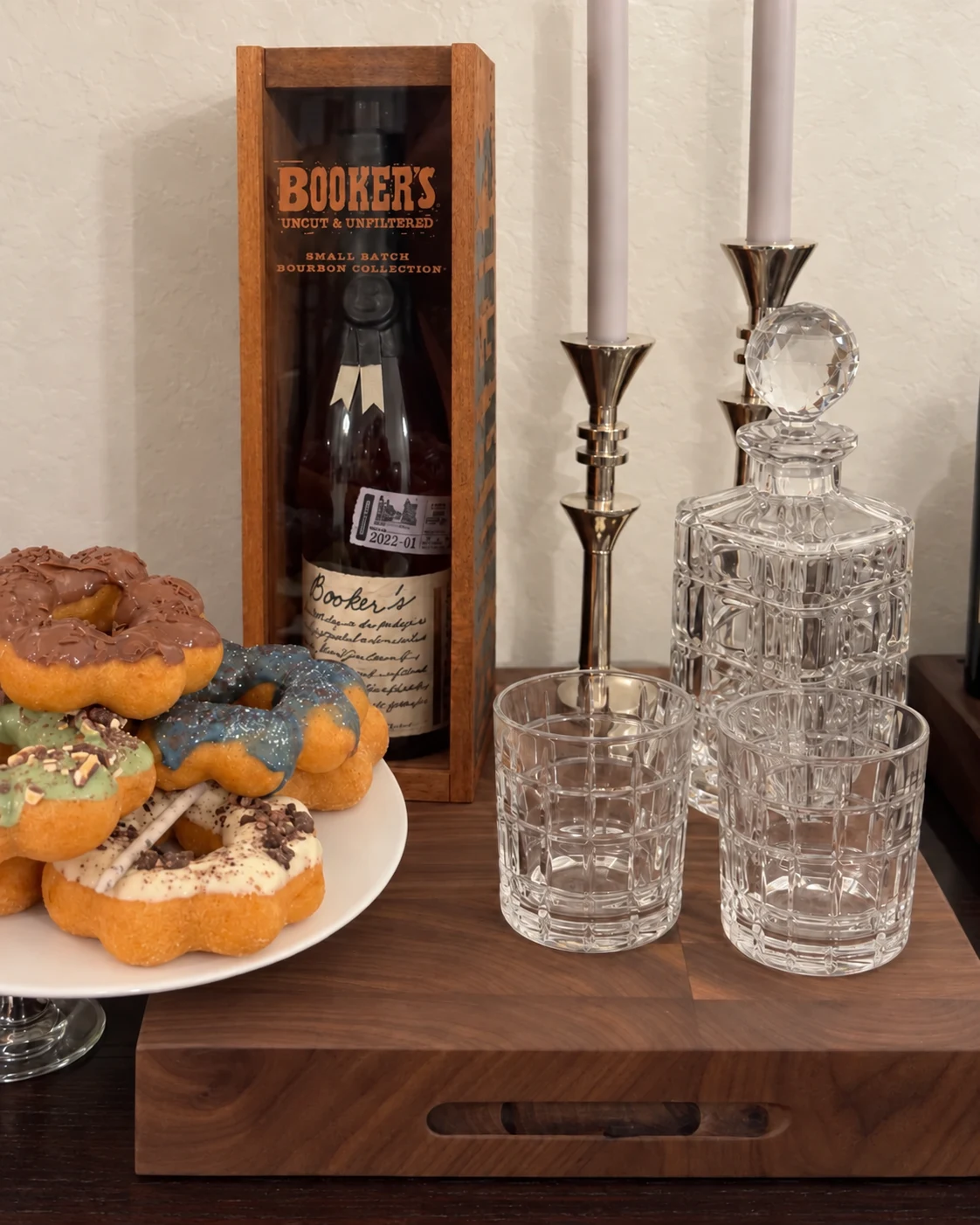Wood serving board displaying a decanter, glasses, and desserts