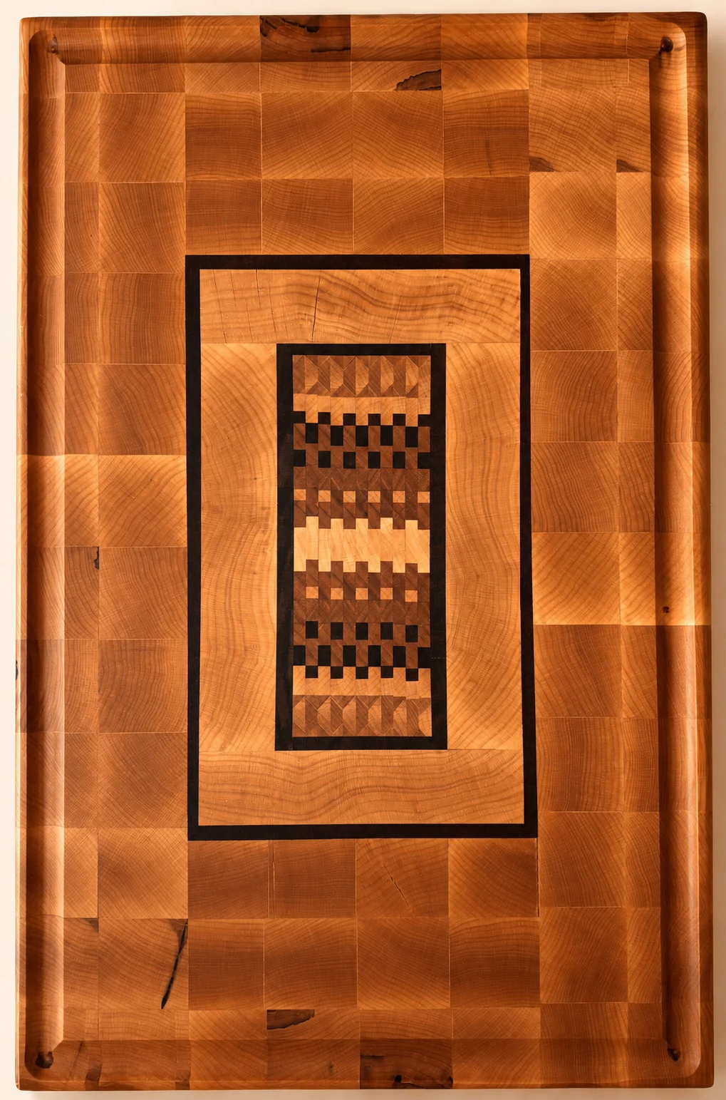 End-grain cutting board composed of maple, walnut, cherry, and wenge in a geometric mosaic