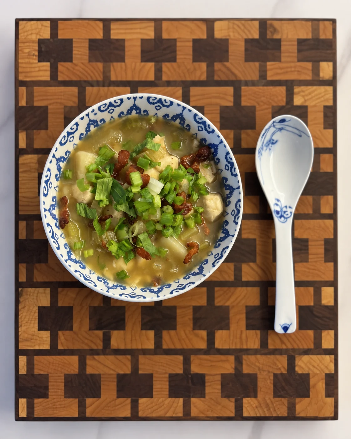 Pixel-pattern end-grain board presented with a bowl and vertically arranged ceramic spoon