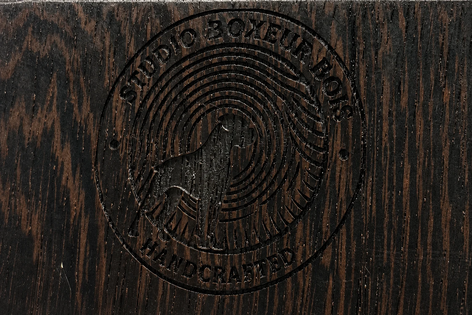 Tightly cropped horizontal detail of the maker's mark with Studio Boxeur Bois engraved across the top